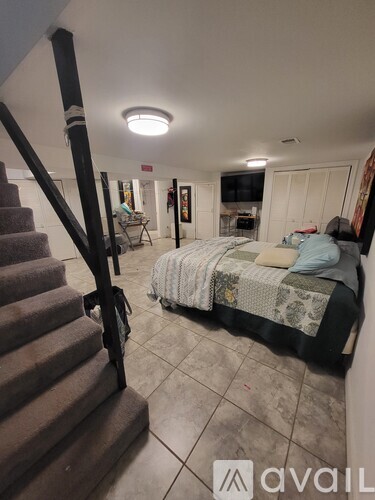 A bedroom with a bed, a couch, and a staircase.