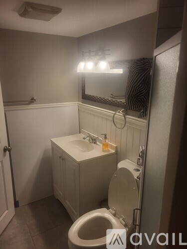 A small bathroom with a toilet, sink, and mirror.