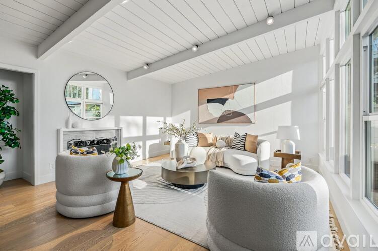 A modern living room with a grey sofa, a round mirror, and a coffee table.