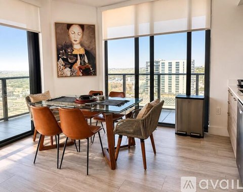 A dining room with a glass table and chairs with a painting on the wall.