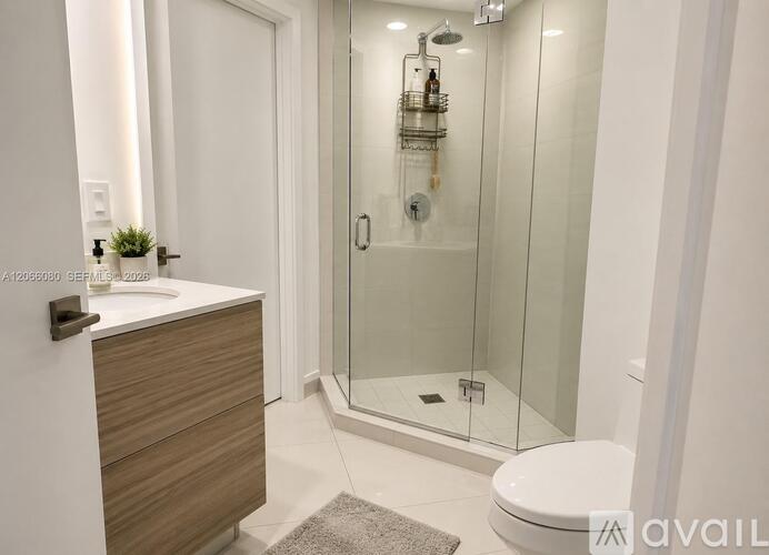 A bathroom with a toilet, sink, and glass shower stall.