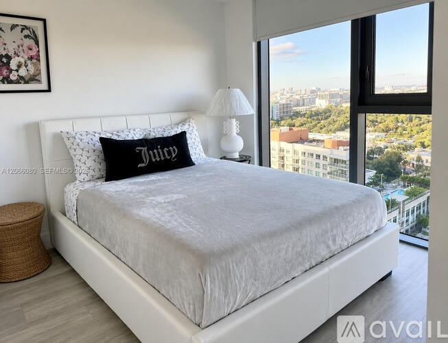 A bedroom with a large bed and a city view through the window.