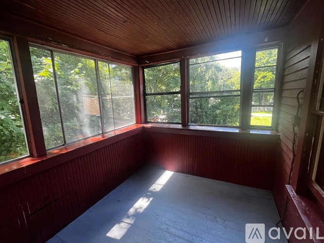 A sunny room with wooden walls and a large window.