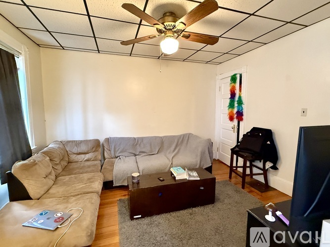 A living room with a beige couch, a coffee table, and a ceiling fan.