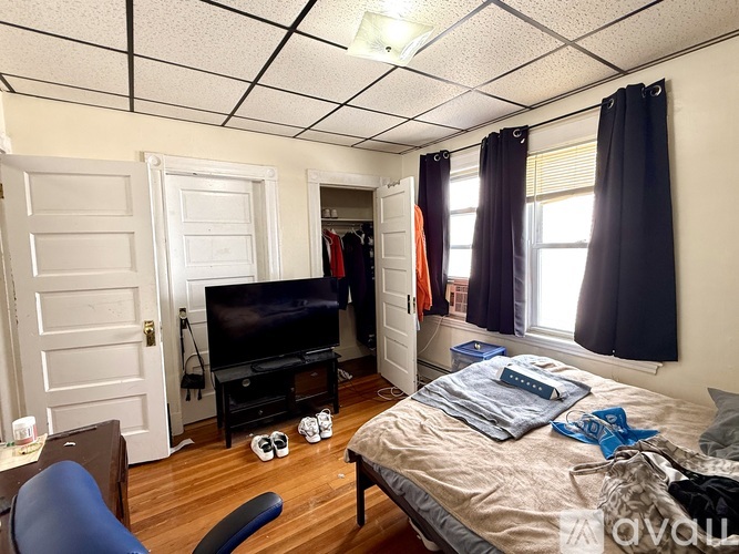 A bedroom with a bed, chair, and a television.