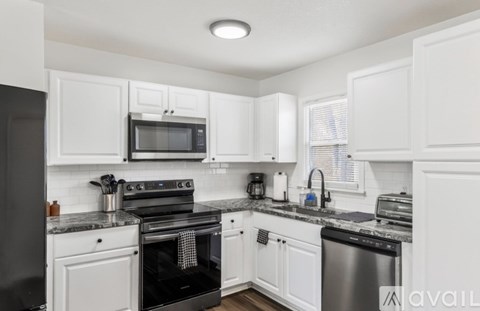 A kitchen with white cabinets and black appliances.