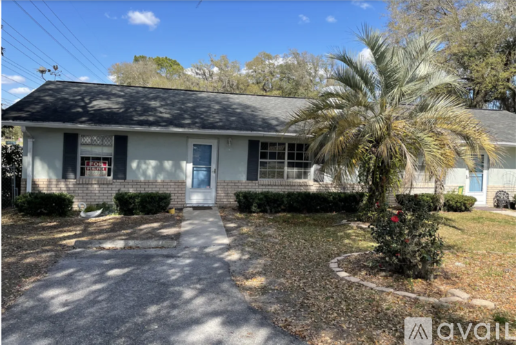 A house with a driveway and a palm tree in front.