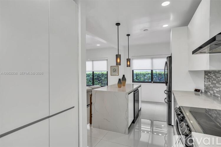 A modern kitchen with a white countertop and stainless steel appliances.