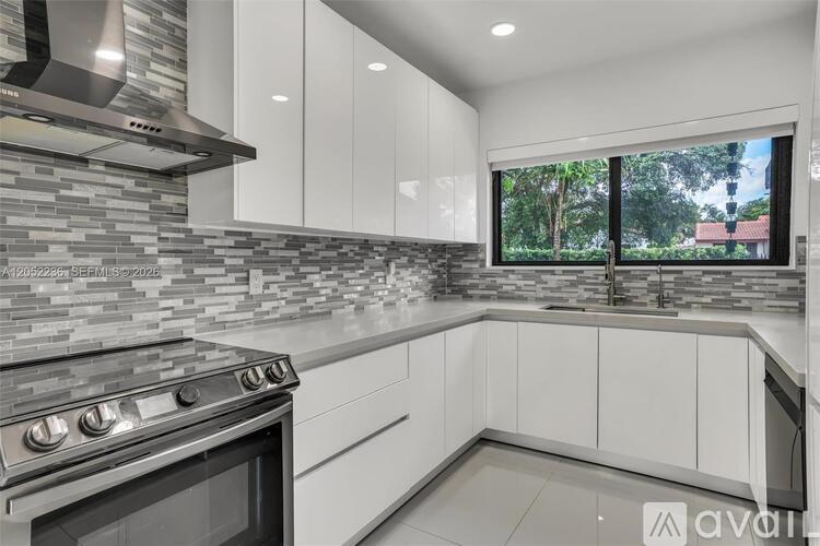A modern kitchen with a stone backsplash and white cabinets.
