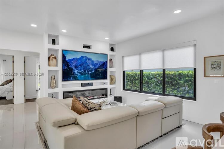 A modern living room with a large sectional sofa and a flat-screen TV mounted on the wall.