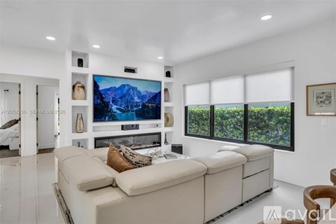 A modern living room with a large sectional sofa and a flat-screen TV mounted on the wall.