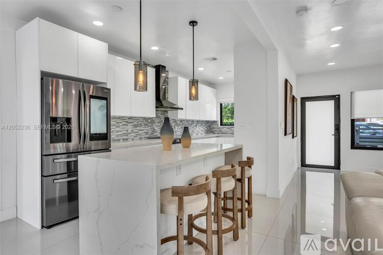 A modern kitchen with a marble countertop and stainless steel appliances.