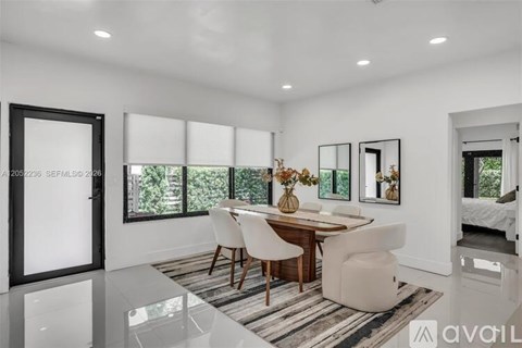 A modern dining room with a wooden table and white chairs.