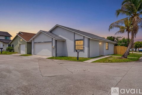 A house with a garage and a palm tree in front.