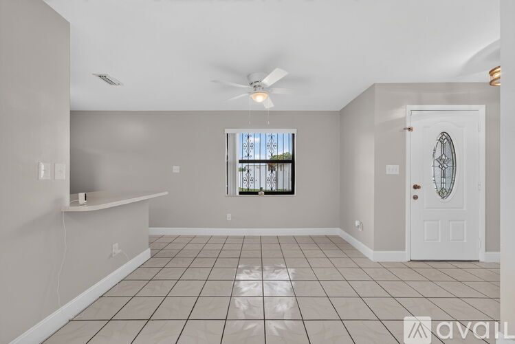 A spacious room with a ceiling fan and a window with a view of trees.