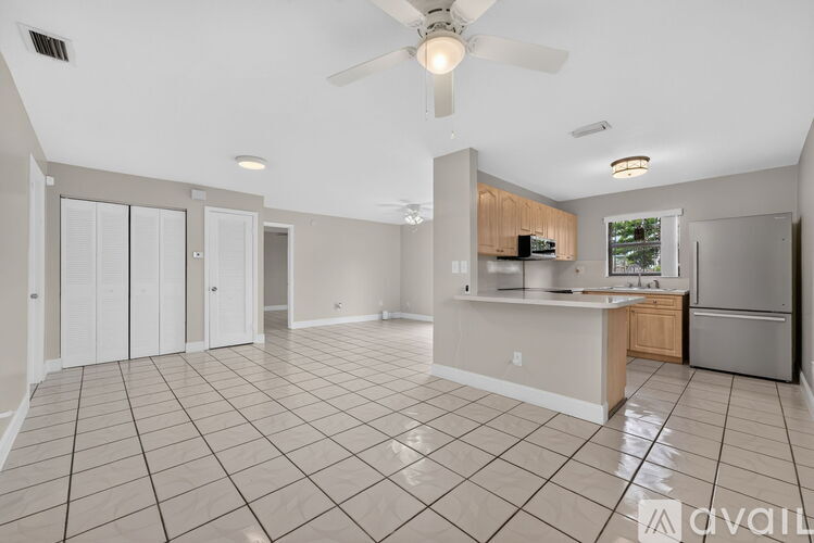 A spacious kitchen and living room with tile flooring and a ceiling fan.