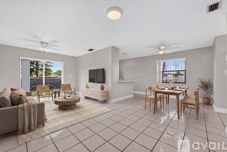 A living room with a couch, chairs, a television, and a dining table.