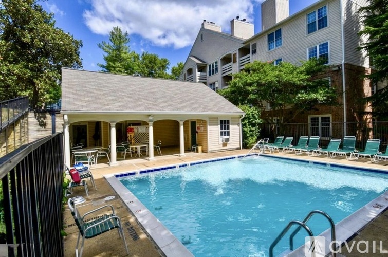 A pool with chairs around it and a house in the background.