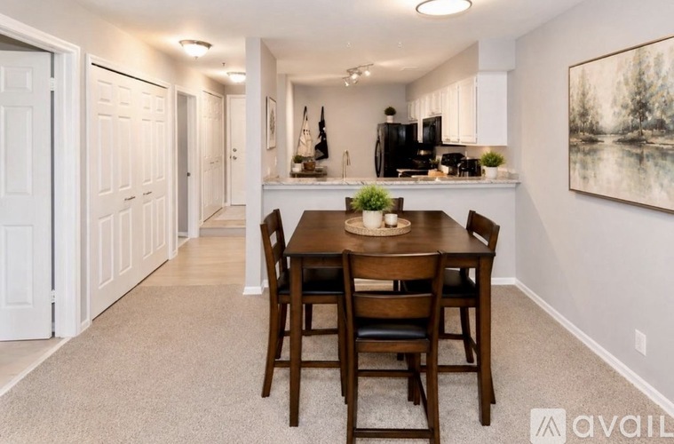 A dining room with a table set for two and a kitchen in the background.