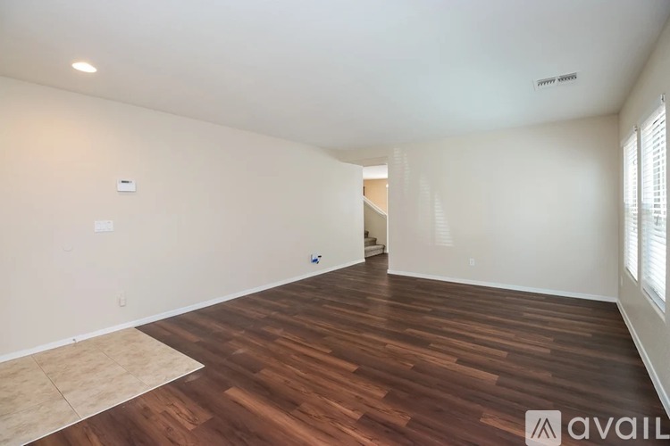 A spacious room with wooden flooring and white walls.