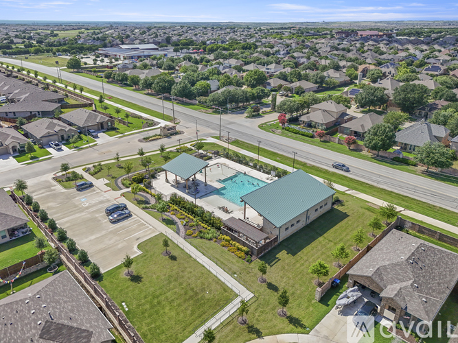 A bird's eye view of a suburban area with a swimming pool and a building with a green roof.