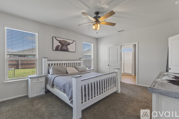 A bedroom with a bed, a ceiling fan, and a picture of a bull on the wall.