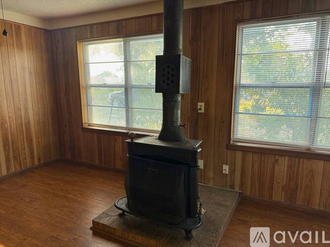 A wood stove in a room with wooden walls and a window.