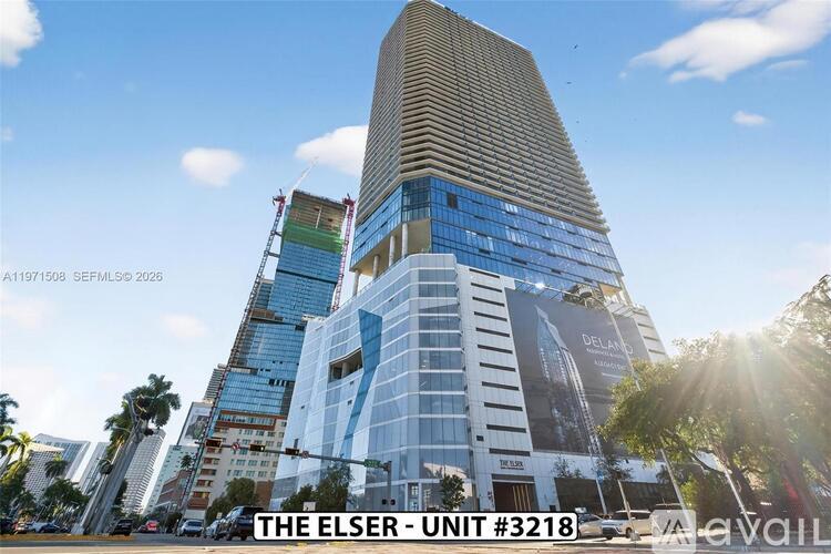 A tall building with a curved top and a sign that reads "THE ELSER - UNIT #3218" is shown.