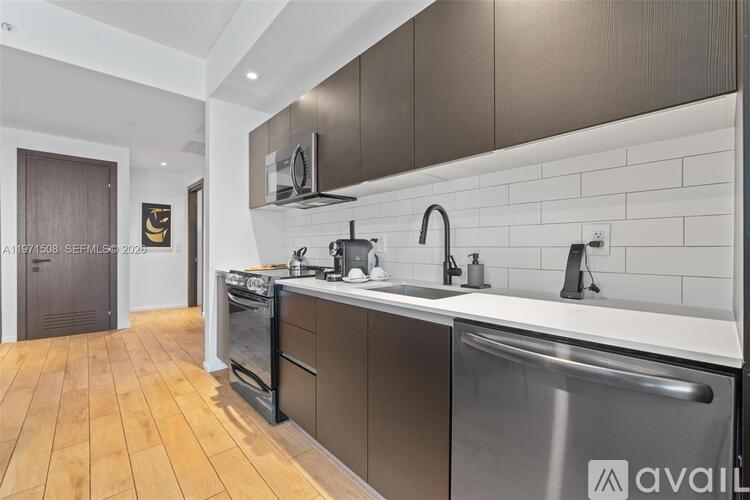 A modern kitchen with stainless steel appliances and wooden flooring.