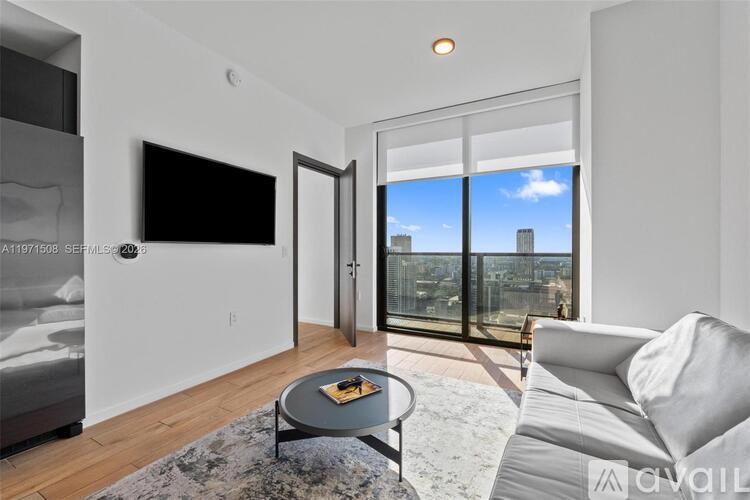 A modern living room with a flat screen TV and a view of the city.