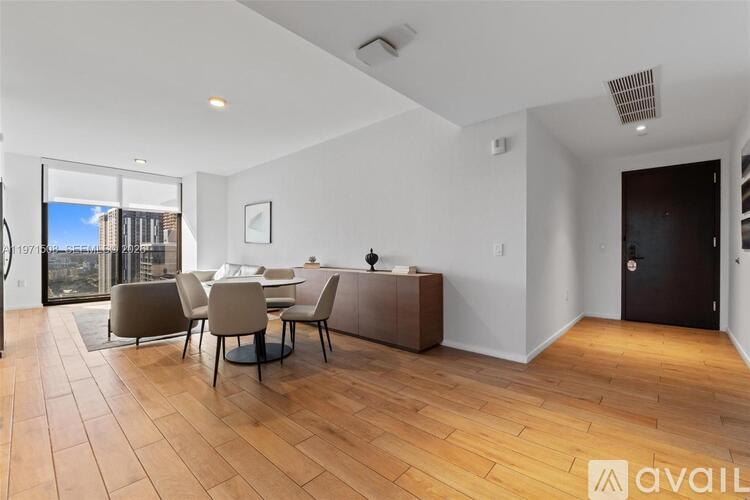 A modern dining room with a wooden floor and a glass door leading to a balcony.