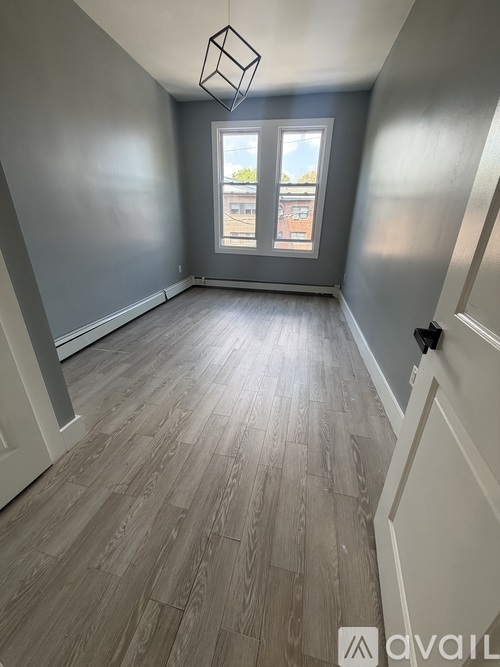 A room with wooden flooring and a window showing a view of buildings outside.
