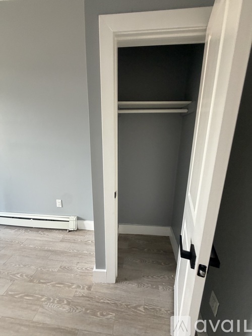 A white door is open to a room with a wall-mounted air conditioner and a tiled floor.