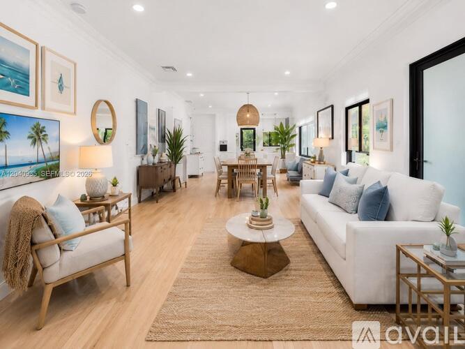 A well-lit, spacious living room with a white sofa, wooden furniture, and a rug.