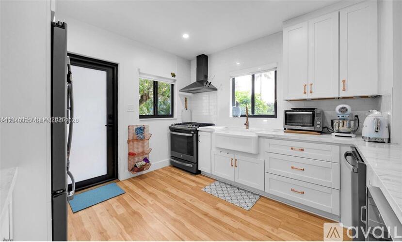 A kitchen with white cabinets and a black fridge.