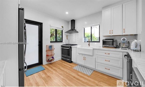 A kitchen with white cabinets and a black fridge.