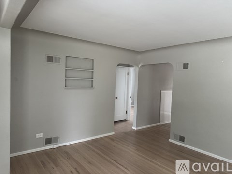 A spacious room with wooden flooring and white walls.