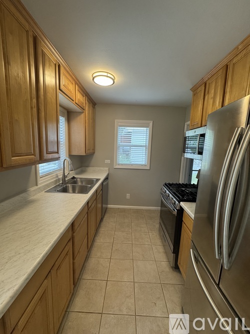A kitchen with wooden cabinets and a stainless steel refrigerator.