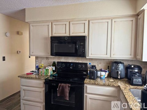 A kitchen with a black oven and white cabinets.
