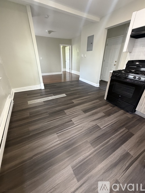 A kitchen with a black stove top oven and wooden flooring.