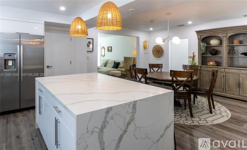 A modern kitchen with a marble island and pendant lights.