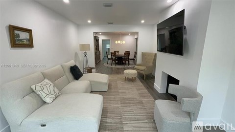 A living room with a grey couch and a television on the wall.