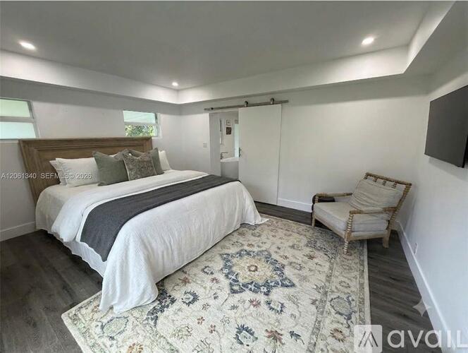 A bedroom with a large bed and a chair.