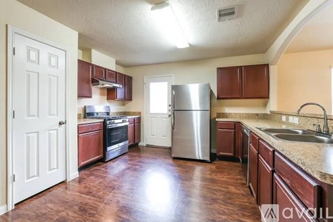 A kitchen with brown cabinets and a stainless steel refrigerator.