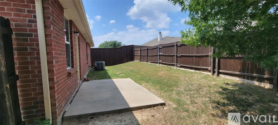 A backyard with a brick building, a wooden fence, and a tree.