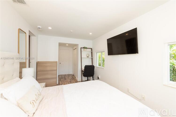 A bedroom with a large bed and a flat screen TV mounted on the wall.