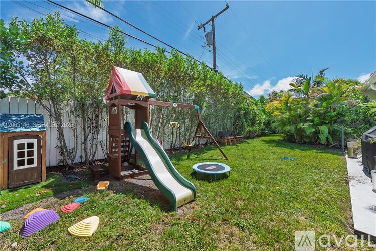 A playground with a green slide and a wooden playhouse.