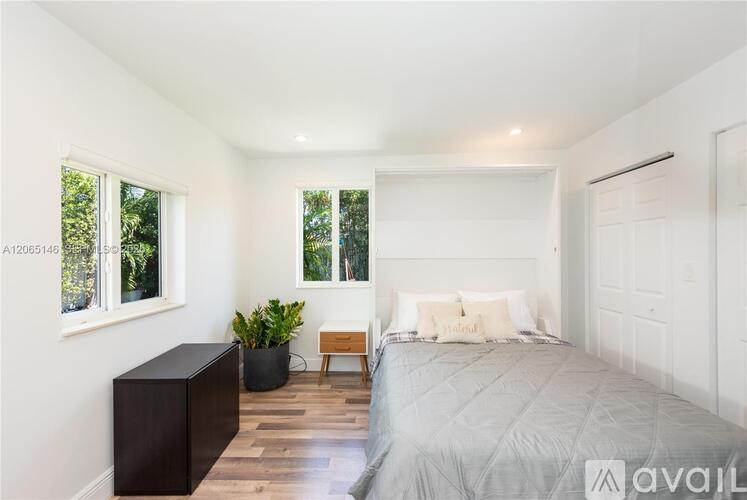 A bedroom with a large bed, a wooden bench, and a potted plant.