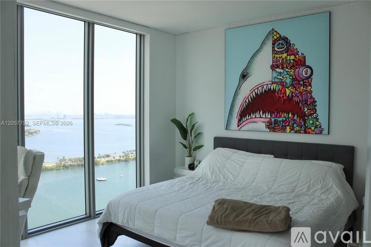 A bedroom with a large bed and a shark painting on the wall.