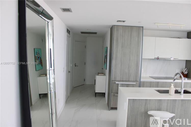 A modern kitchen with white cabinets and a marble countertop.
